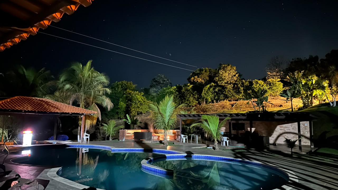Vista noturna da piscina e da vegetação